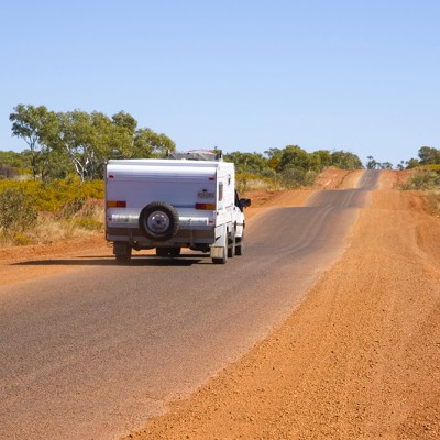 Back view of folding caravan being towed on a bumpy road in outback Queensland, Australia